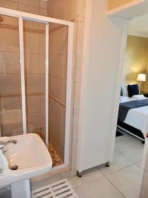 a bathroom with a shower and a sink and a bed at Mountain Mist in Bettyʼs Bay