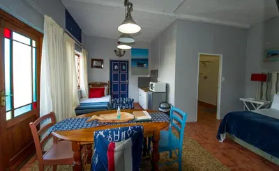 a room with a table and chairs and a bedroom at @Abelia Guest House in Somerset West