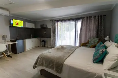 a bedroom with a large bed with a television on the wall at @Abelia Guest House in Somerset West