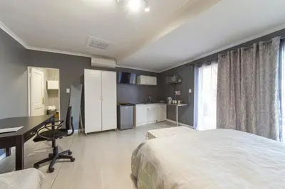 a bedroom with a bed and a desk and a computer at @Abelia Guest House in Somerset West