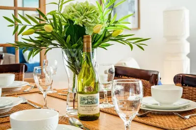 a table with a bottle of wine and a vase with flowers at Marechale Way in Cape Town