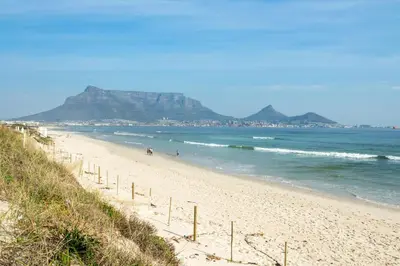 a beach with people walking on the sand and the ocean at Marechale Way in Cape Town