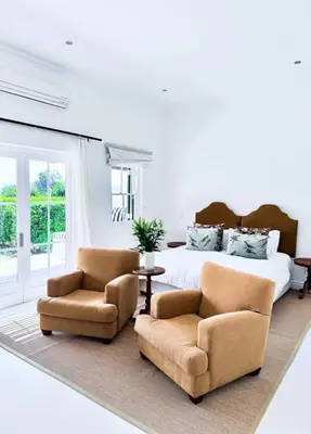 a bedroom with a bed and two chairs at Huguenot House in Franschhoek
