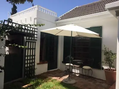a patio with an umbrella and a table and chairs at Delightful Surrey Street in Cape Town
