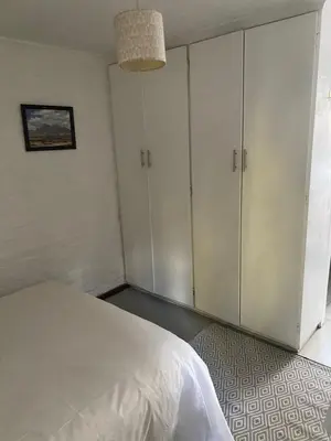 a bedroom with white cabinets and a bed at Delightful Surrey Street in Cape Town