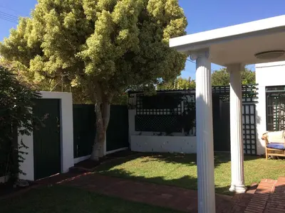 a backyard with a white fence and a tree at Delightful Surrey Street in Cape Town