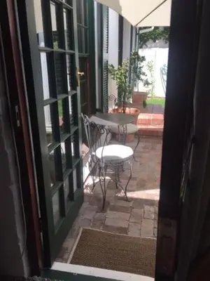an open door to a patio with a table and a chair at Delightful Surrey Street in Cape Town