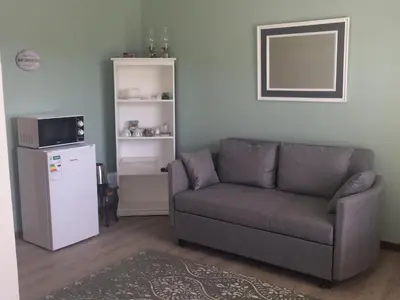 a living room with a couch and a refrigerator at Koraalboom Guesthouse in Wolseley