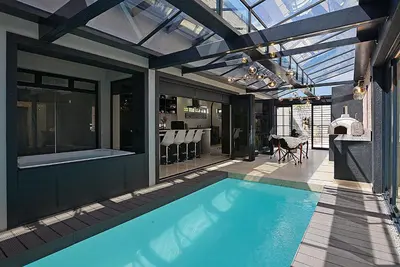 a swimming pool in a house with a glass ceiling at Crown Comfort - Affordable luxury - Private Heated Pool & Hot Tub Under Roof in Cape Town