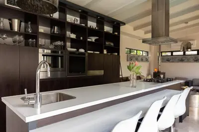 a kitchen with a sink and a counter with white chairs at Crown Comfort - Affordable luxury - Private Heated Pool & Hot Tub Under Roof in Cape Town