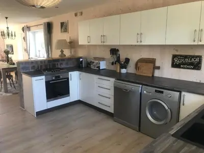 a kitchen with white cabinets and a washer and dryer at African Holiday home in Table View in Cape Town