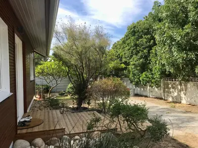 a backyard of a house with a fence and trees at African Holiday home in Table View in Cape Town