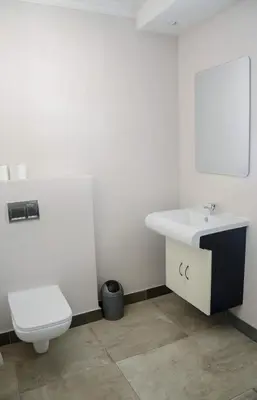 a white bathroom with a toilet and a sink at Pringle Nest in Cape Town