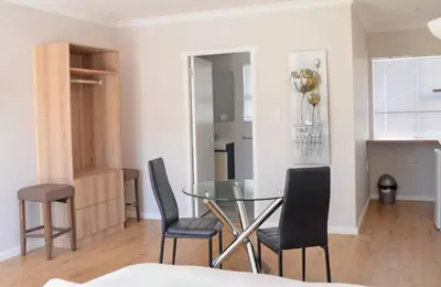 a dining room with a glass table and chairs at Pringle Nest in Cape Town