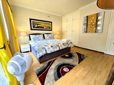 a bedroom with a bed with a fan and a rug at Walters Lane Luxury Accommodation main house - No loadshedding in Cape Town