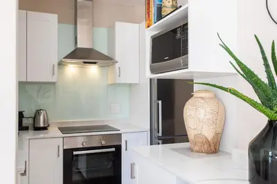 a kitchen with white cabinets and a vase at Koetsiershuis in Stellenbosch