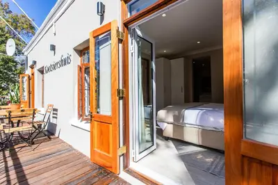 a door to a bedroom with a bed on a porch at Koetsiershuis in Stellenbosch
