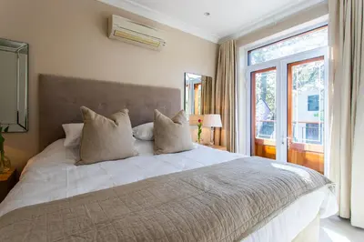 a bedroom with a large white bed and a window at Koetsiershuis in Stellenbosch
