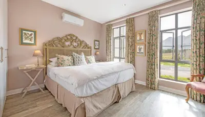 a bedroom with a large bed and two windows at The Lemon Tree in Franschhoek in Franschhoek