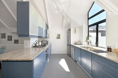 a kitchen with blue cabinets and a large window at No. 6 The Yard in Franschhoek
