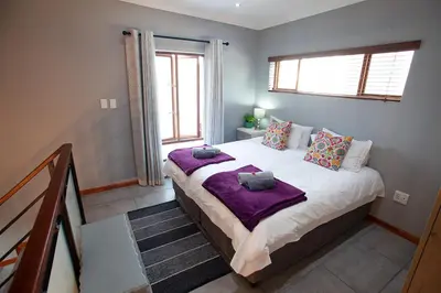 a bedroom with a large bed with purple blankets at Culemborg Cottage in Cape Town