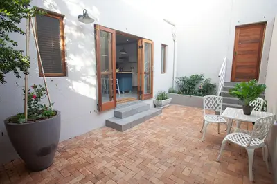 a patio with two chairs and a table and a building at Culemborg Cottage in Cape Town