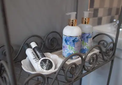 a shelf with two bottles of soap and a mirror at Culemborg Cottage in Cape Town