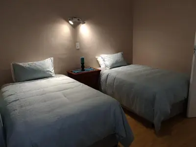 a bedroom with two beds and a night stand with a lamp at TwinnPalms Accommodation in Cape Town