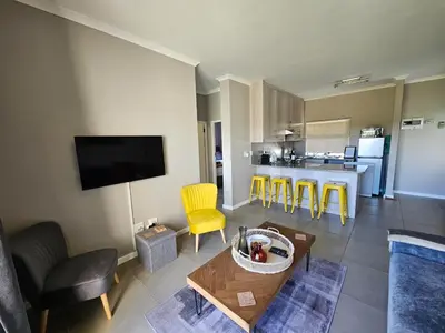 a living room with a table and yellow chairs at Nemesia Court in Durbanville