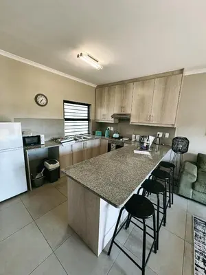 a kitchen with a large island in the middle with bar stools at Nemesia Court in Durbanville