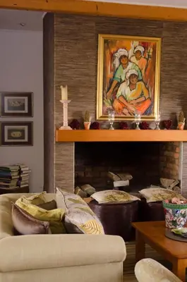 a living room with a couch and a painting above a fireplace at Rouxwil Country House in Caledon