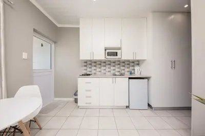 a white kitchen with white cabinets and a microwave at Villa Eike in Grabouw