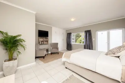a bedroom with a white bed and a dining room at Villa Eike in Grabouw