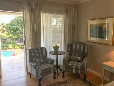 two chairs and a table in a living room with a window at Lavender Suite in Cape Town