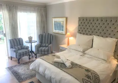 a bedroom with a large bed and two chairs at Lavender Suite in Cape Town