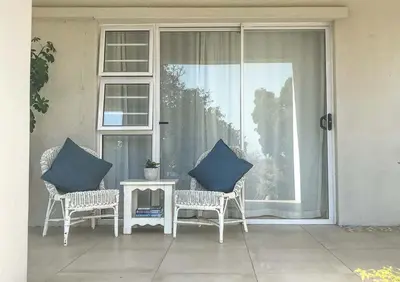 a porch with two chairs and a table with blue pillows at Lavender Suite in Cape Town