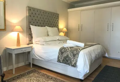a bedroom with a large white bed with a headboard at Lavender Suite in Cape Town