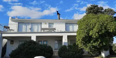 a white house with a balcony on top of it at Beach Cottage 1 in Hermanus