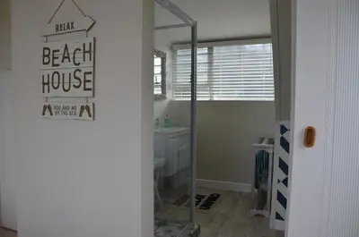 a bathroom with a shower and a sink and a mirror at Beach Cottage 1 in Hermanus
