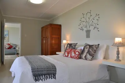 a bedroom with a white bed with pillows on it at Beach Villa Apartment in Hermanus