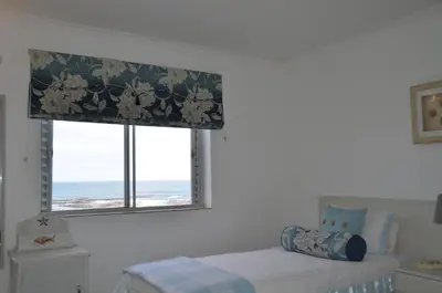 a bedroom with a bed and a window with a curtain at Beach Villa Apartment in Hermanus