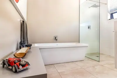 a bathroom with a white tub and a red toy car on a counter at Stellar Guest Villa on Stunning Wine Farm in Cape Town