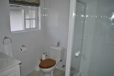 a white bathroom with a toilet and a shower at Cotswold House Residence in Cape Town