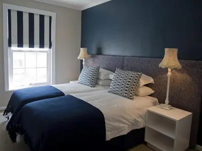 a bedroom with a large bed with blue and white at Kenjockity Self Catering Apartments in Hermanus