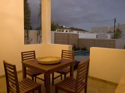 a wooden table with chairs and a basket on a patio at Kenjockity Self Catering Apartments in Hermanus
