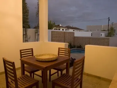 a wooden table with chairs and a basket on a patio at Kenjockity Self Catering Apartments in Hermanus