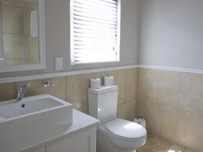 a bathroom with a toilet and a sink and a window at Kenjockity Self Catering Apartments in Hermanus