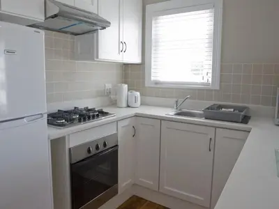 a white kitchen with a stove and a sink at Kenjockity Self Catering Apartments in Hermanus