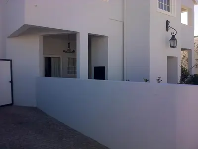 a white wall with a mirror on the side of a building at Kenjockity Self Catering Apartments in Hermanus