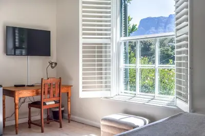 a bedroom with a desk and a window at Sandown Lodge in Cape Town